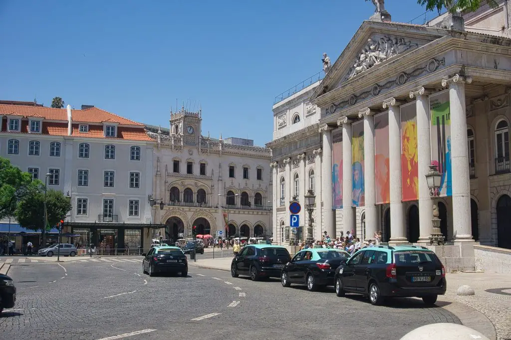 Taxis are parked at the National Theater in Rossio Square in Lisbon.