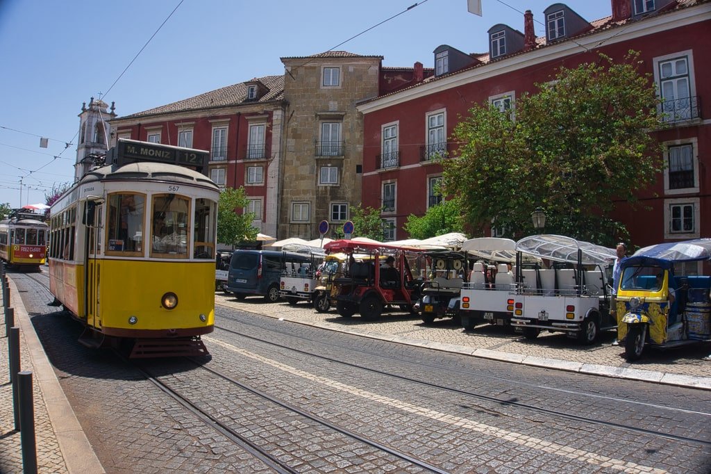 A yellow number 12 tram moves through the streets of Lisbon.