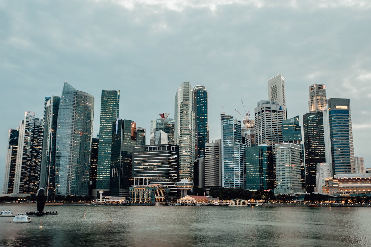 Dramatic view of Singapore's modern skyline from Marina Bay at sunset, reflecting on the water.