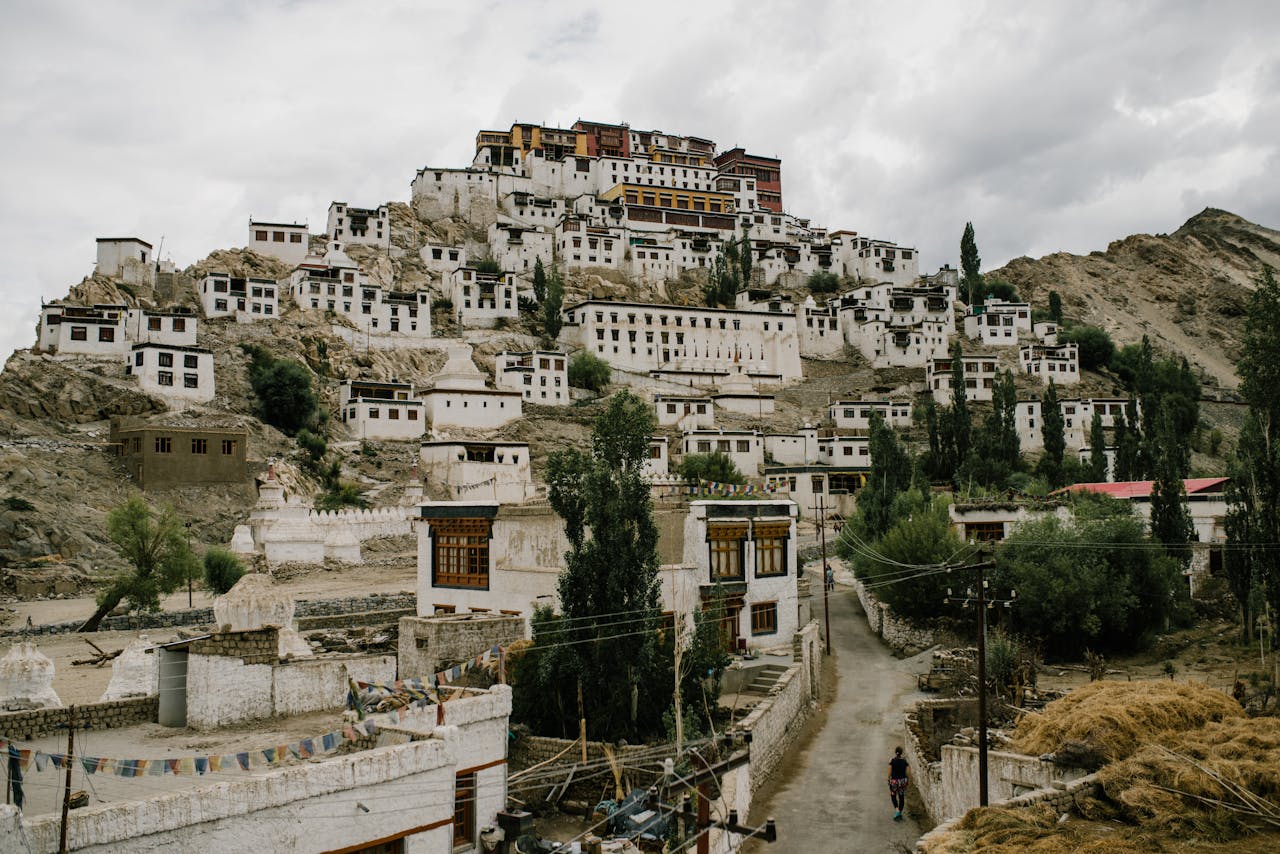 Scenic view of Thiksey Monastery nestled in the mountains of Ladakh, India with overcast skies.